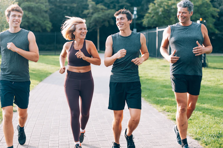 A mother and father jog in a park with their two teenage sons.