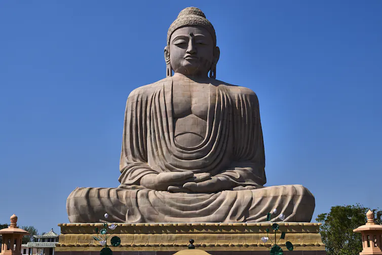A granite statue of a seated Buddha in meditation.