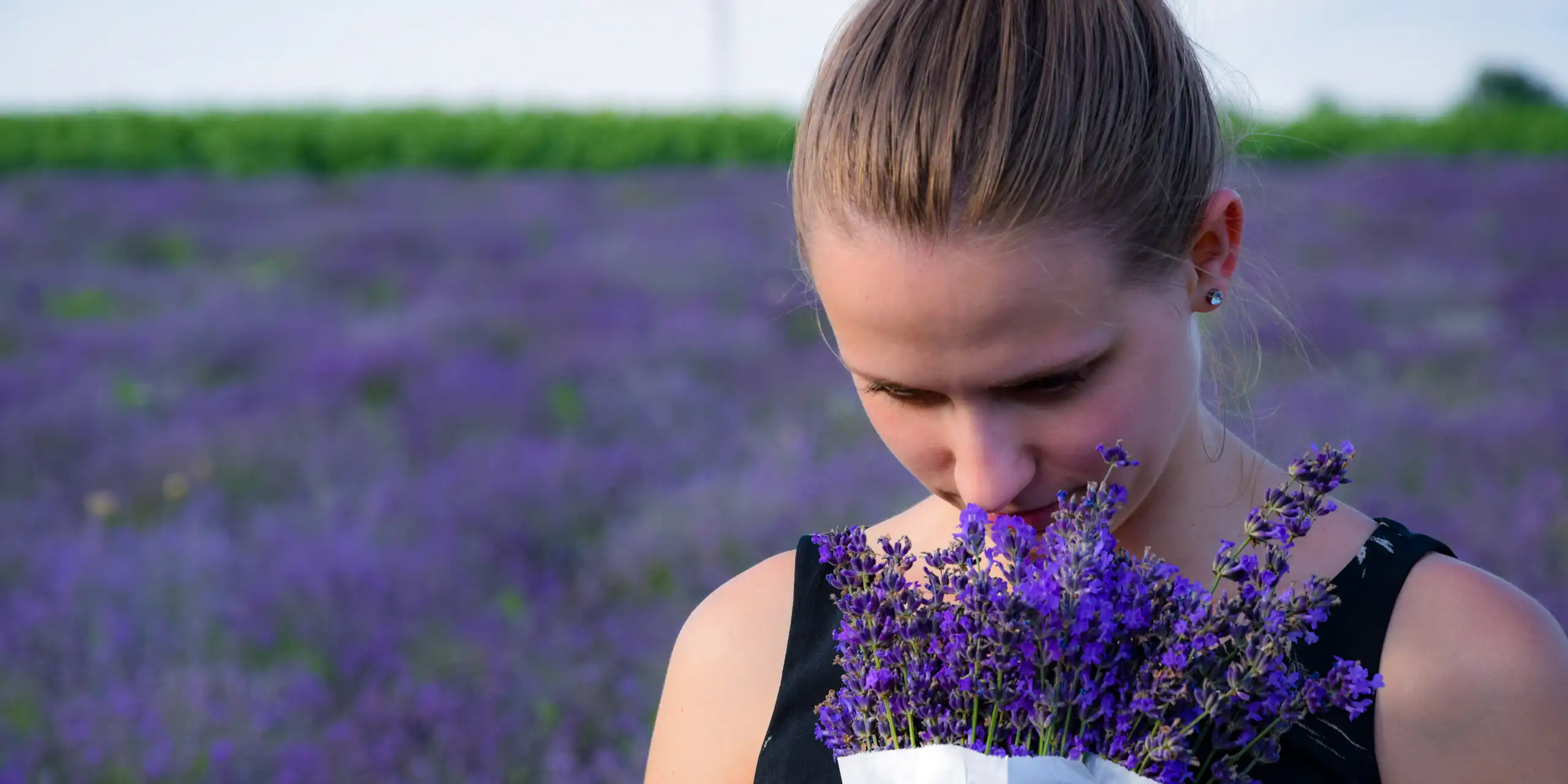 Une femme sent un bouquet de lavande.
