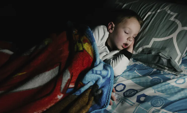 young boy asleep in bed with his mouth open