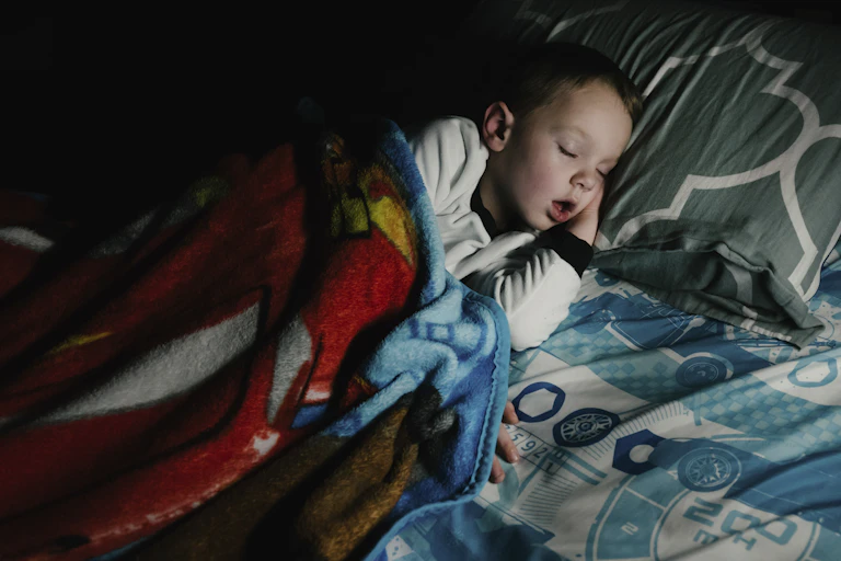 young boy asleep in bed with his mouth open