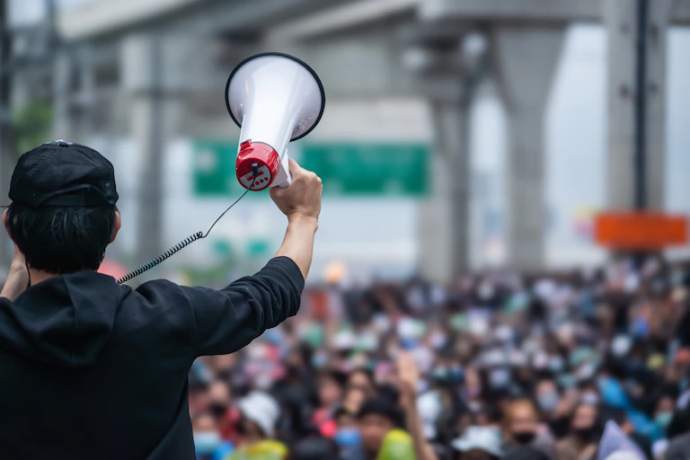 A person with a megaphone addressing a large crowd