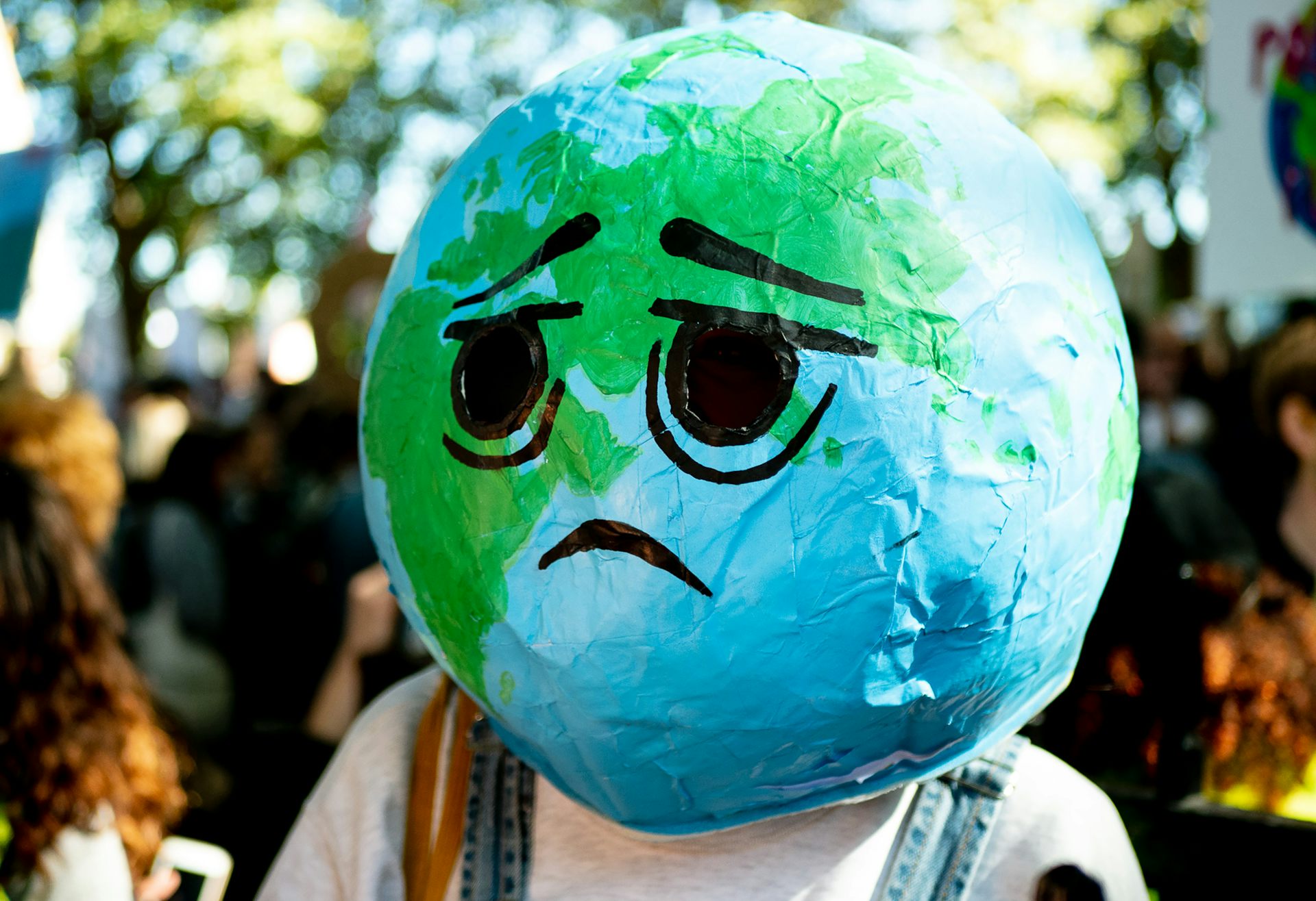 Lors d’une manifestation contre le dérèglement climatique, une personne a recouvert sa tête d'une boule qui représente la planète avec dessus dessiné un visage triste.
