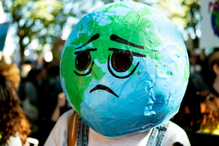 Lors d’une manifestation contre le dérèglement climatique, une personne a recouvert sa tête d'une boule qui représente la planète avec dessus dessiné un visage triste.