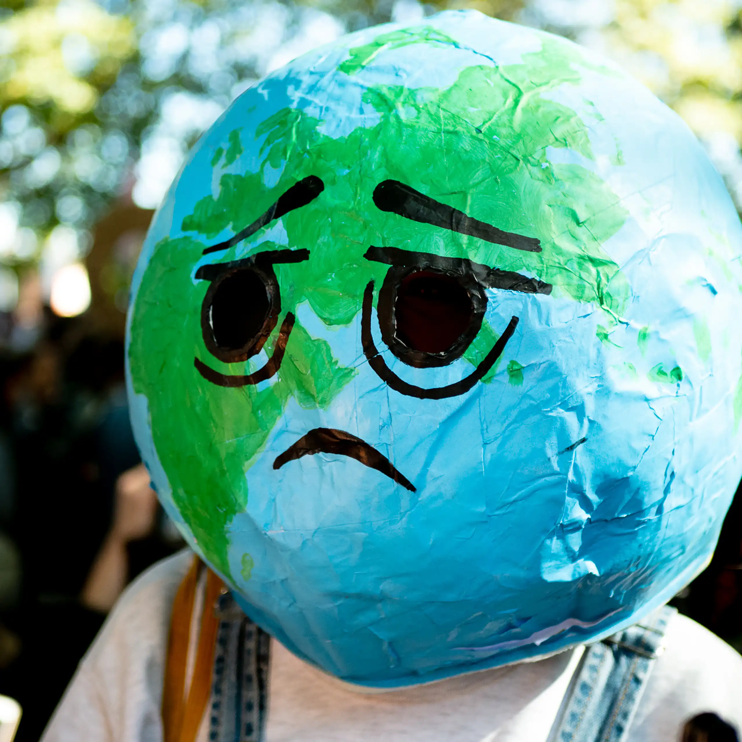 Lors d’une manifestation contre le dérèglement climatique, une personne a recouvert sa tête d'une boule qui représente la planète avec dessus dessiné un visage triste.