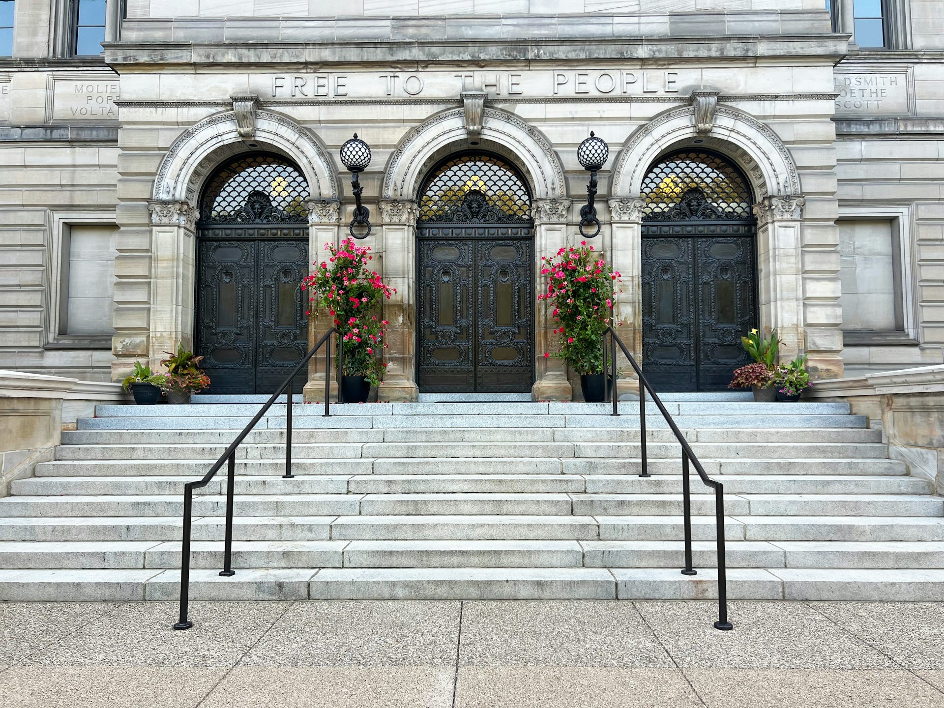 Wide steps with two railings leading up to three arched doorways of Beaux-Arts building