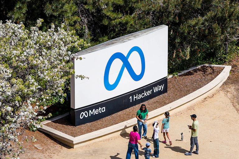 six people stand in fron tof a large sign board that contains a stylized infinity symbol