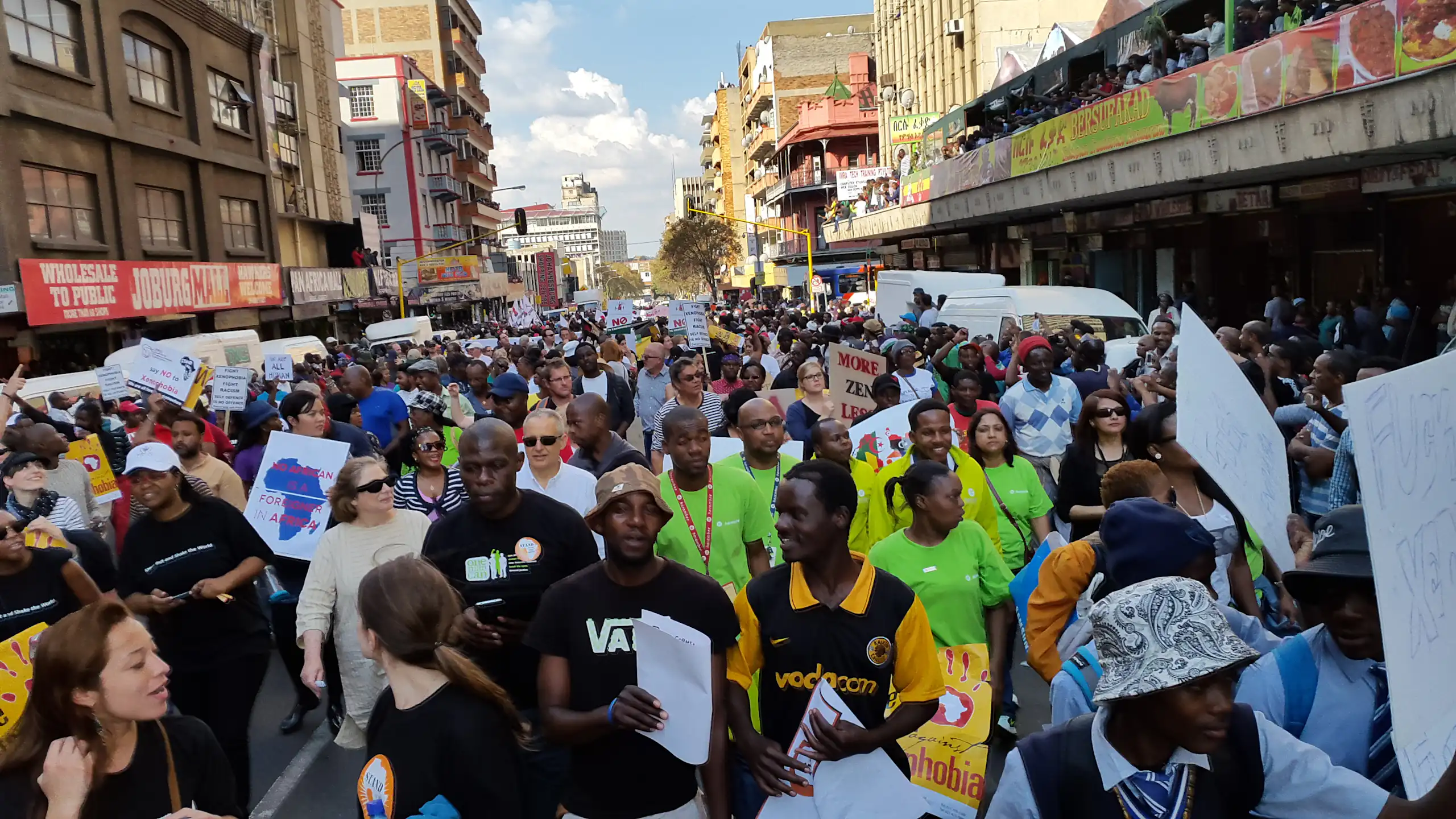 Crowd of people in a street, some holding placards