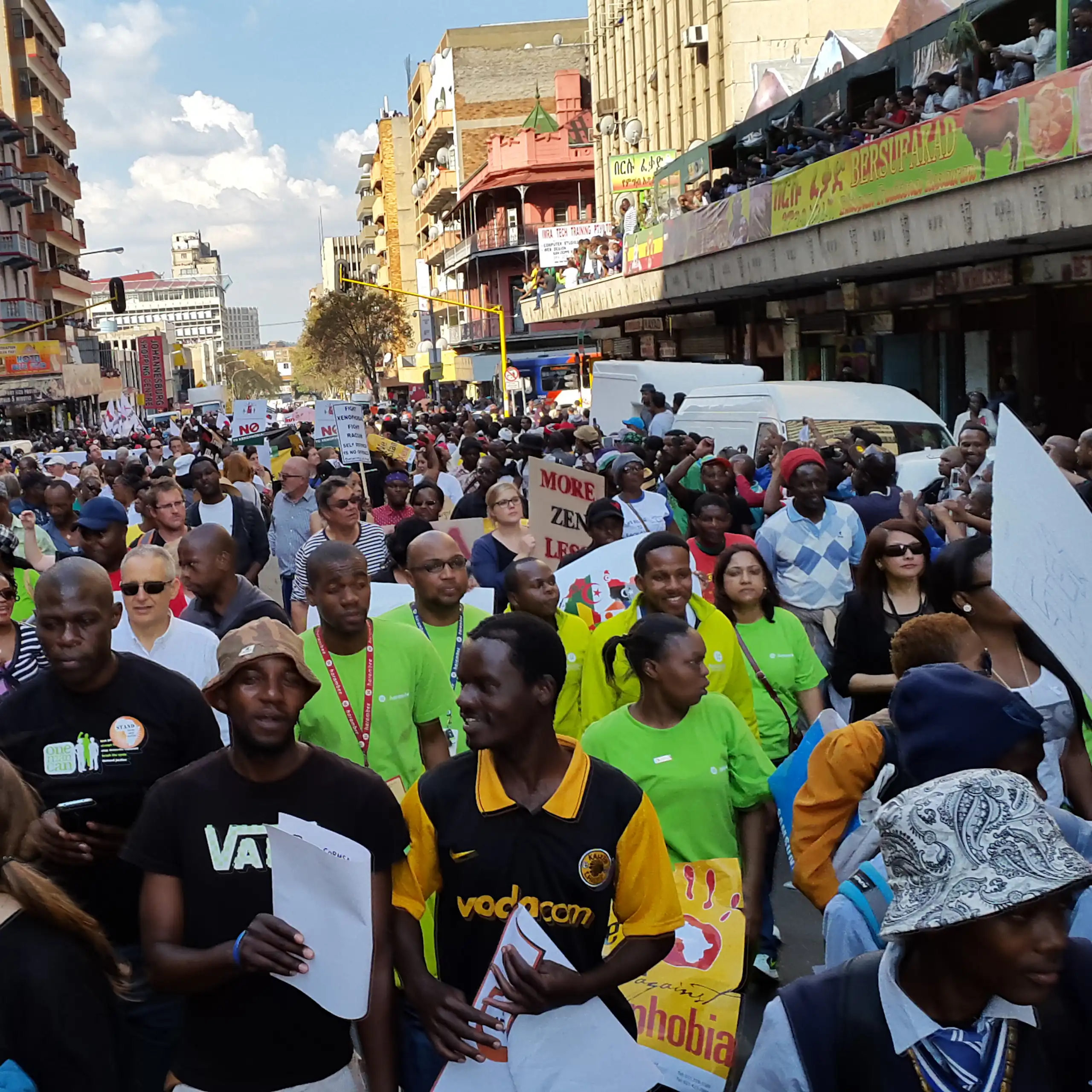 Crowd of people in a street, some holding placards