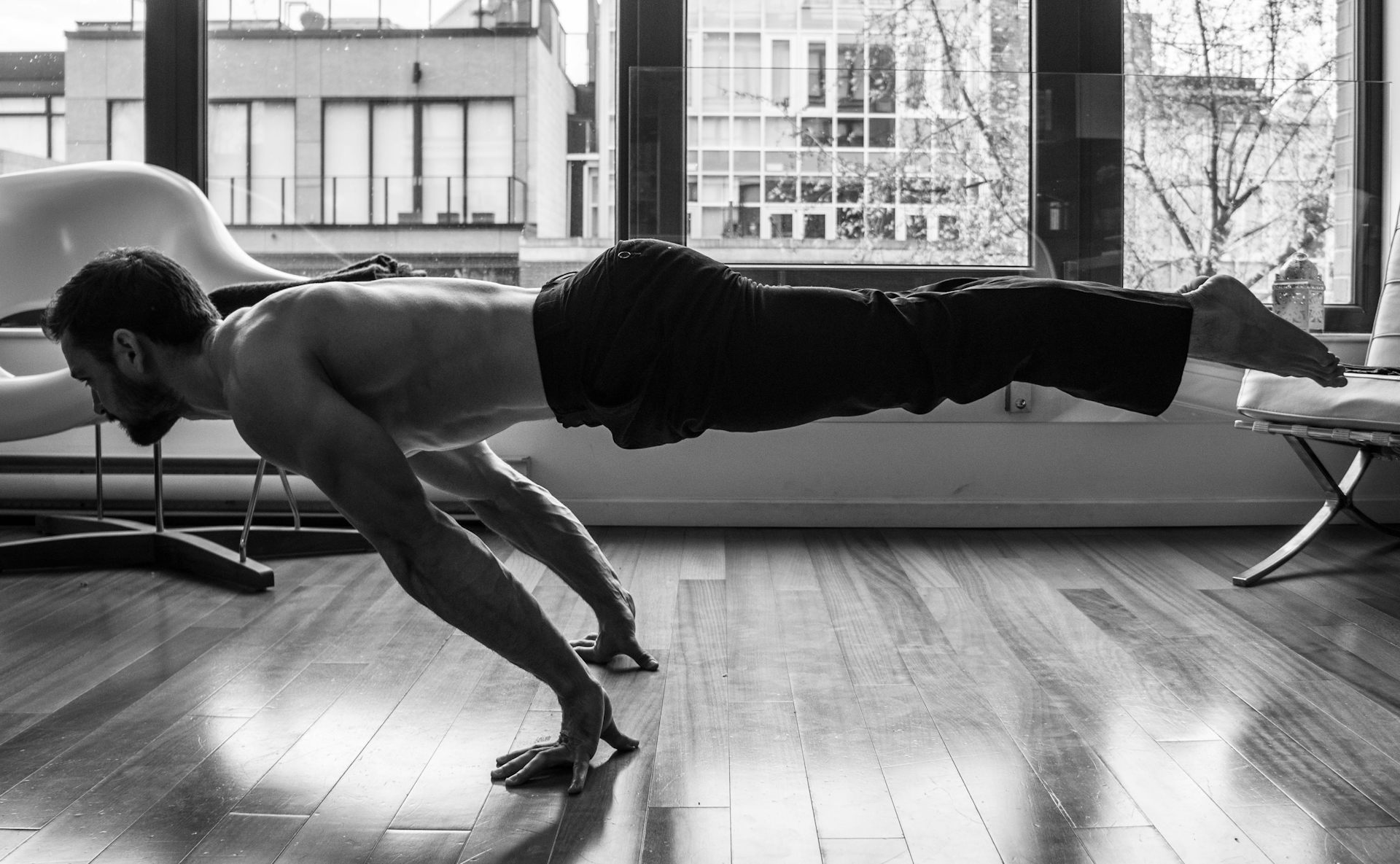 A man holds his body in a horizontal position, with only his hands on the floor.