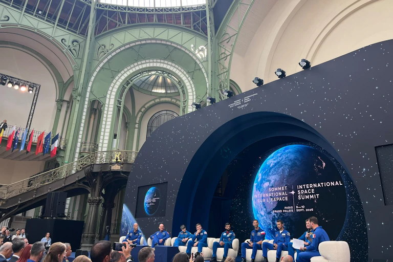 Several astronauts are debating on stage before the summit participants.