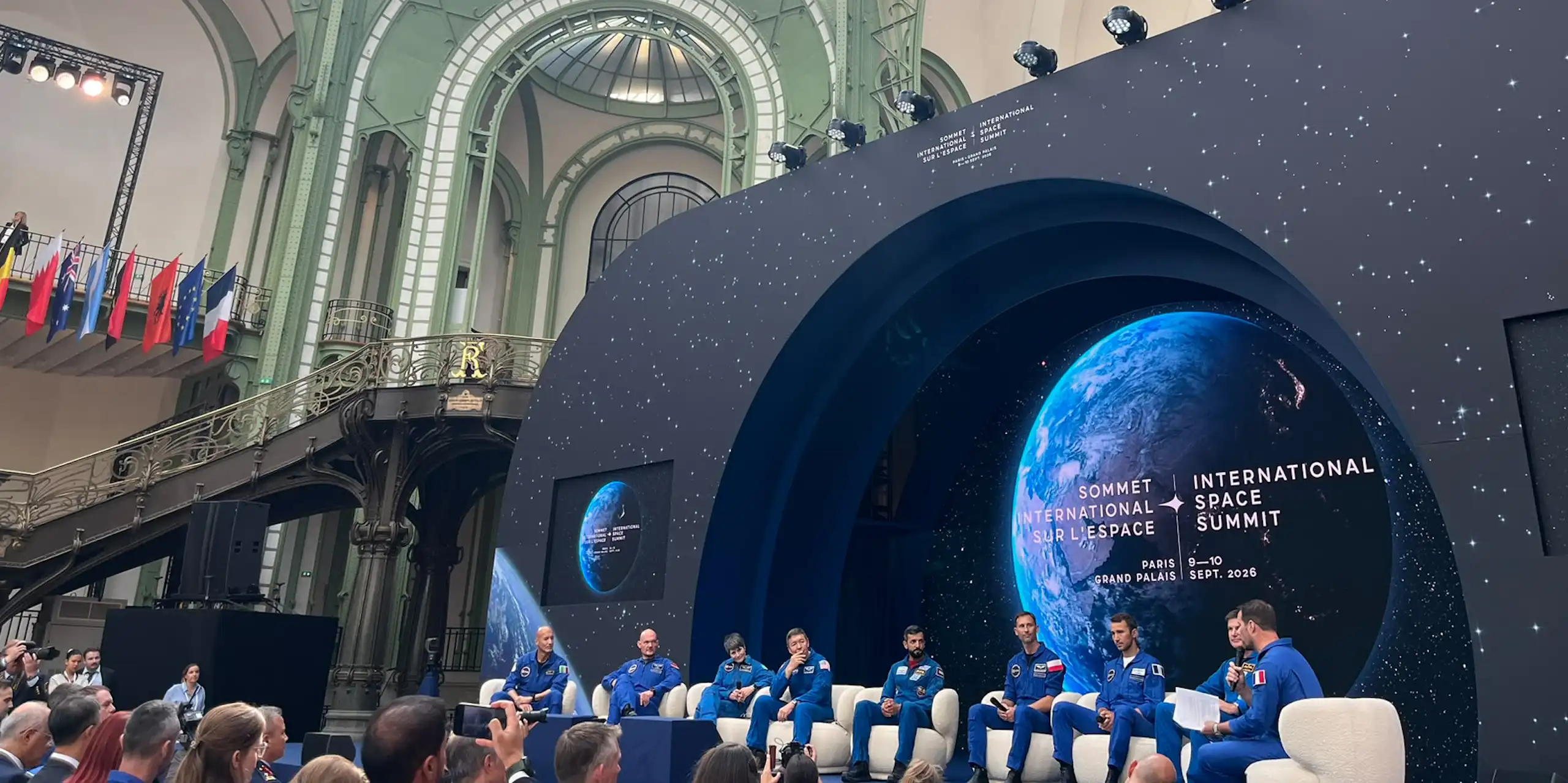 Several astronauts are debating on stage before the summit participants.