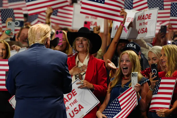A man in suit and tie shakes hands with women dress in red and white.