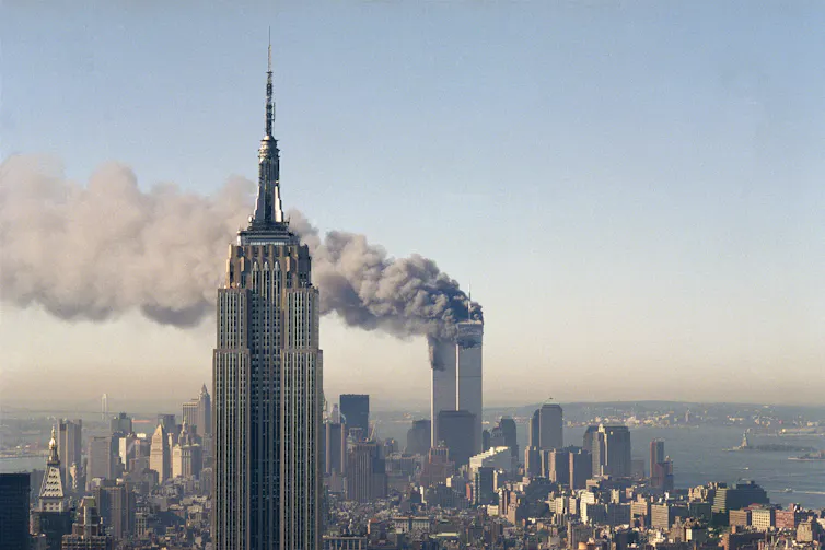Smoke billows from the Twin Towers with the Empire State Building in the foreground
