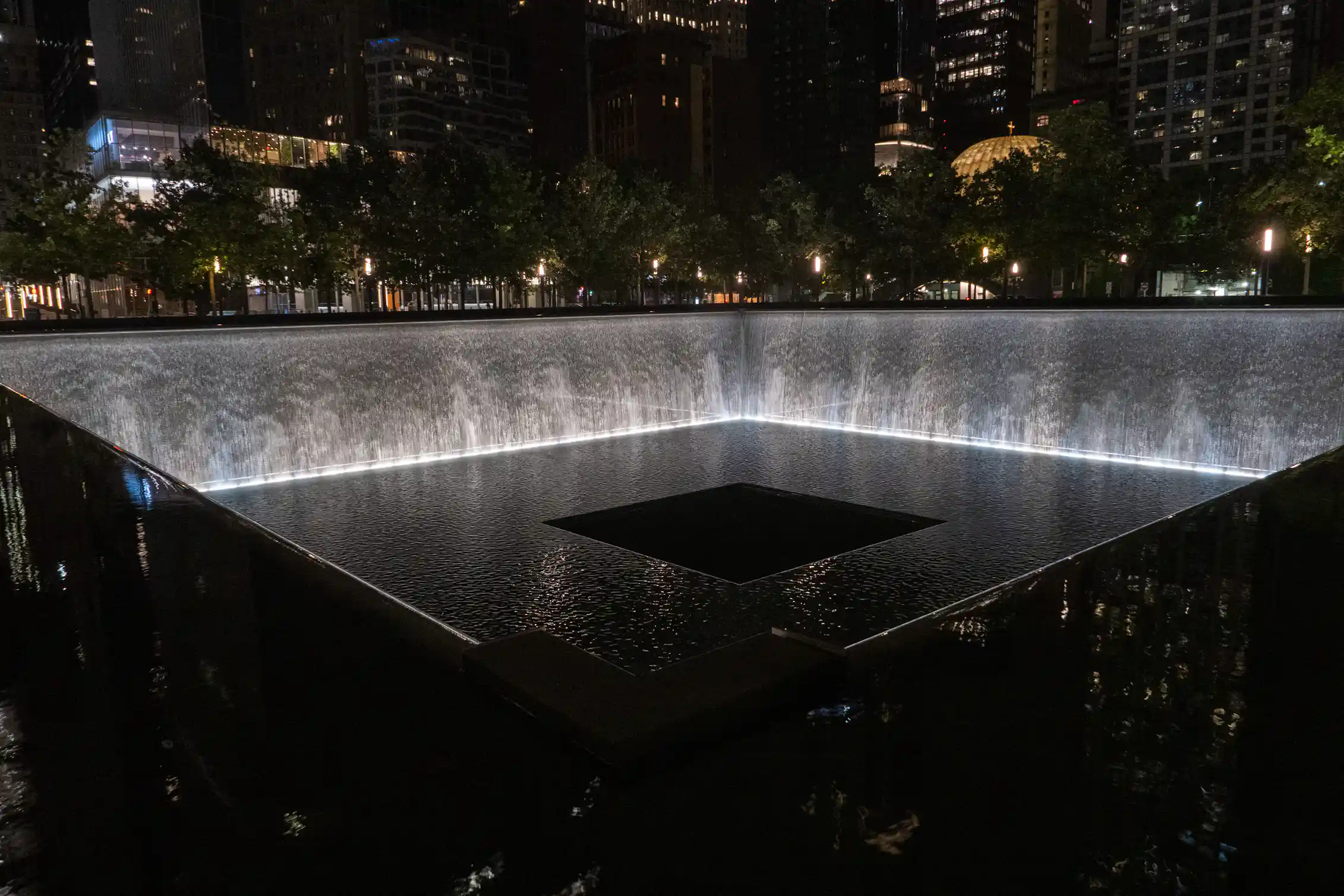 Nighttime view of reflecting pools with waterfalls in the footprint of the Twin Towers.