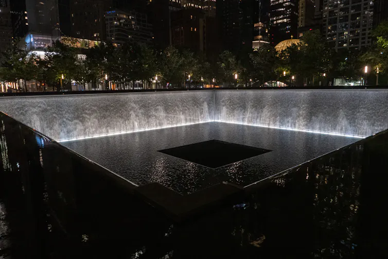 Nighttime view of reflecting pools with waterfalls in the footprint of the Twin Towers.