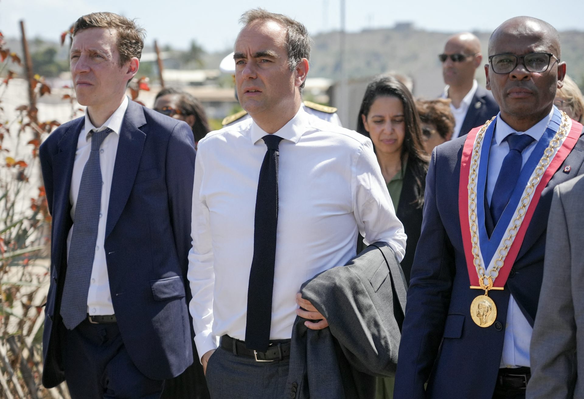 Le Premier ministre français Sébastien Lecornu (au centre), accompagné du ministre français de l'Éducation Édouard Geffray (à gauche), marche aux côtés du maire de Mamoudzou, Ambdilwahedou Soumaïla (à droite), lors de la présentation du projet de rénovation urbaine dans le quartier de Kaweni, au cours de la deuxième journée de sa visite à Mayotte, territoire français de l'océan Indien, le 27 août 2026. 