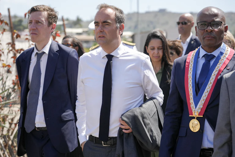 Le Premier ministre français Sébastien Lecornu (au centre), accompagné du ministre français de l'Éducation Édouard Geffray (à gauche), marche aux côtés du maire de Mamoudzou, Ambdilwahedou Soumaïla (à droite), lors de la présentation du projet de rénovation urbaine dans le quartier de Kaweni, au cours de la deuxième journée de sa visite à Mayotte, territoire français de l'océan Indien, le 27 août 2026.