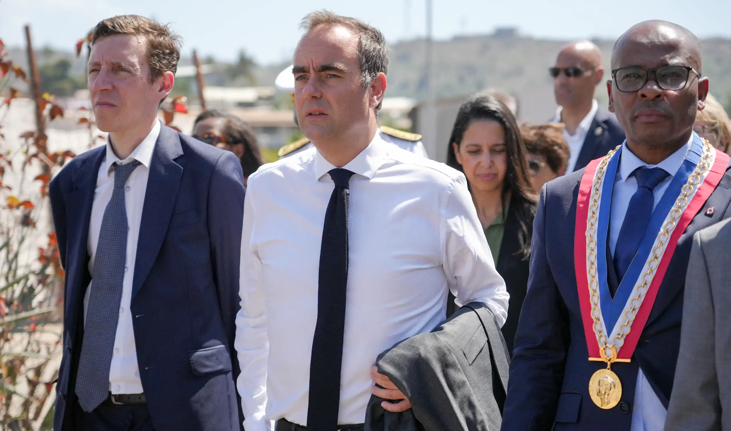Le Premier ministre français Sébastien Lecornu (au centre), accompagné du ministre français de l'Éducation Édouard Geffray (à gauche), marche aux côtés du maire de Mamoudzou, Ambdilwahedou Soumaïla (à droite), lors de la présentation du projet de rénovation urbaine dans le quartier de Kaweni, au cours de la deuxième journée de sa visite à Mayotte, territoire français de l'océan Indien, le 27 août 2026.