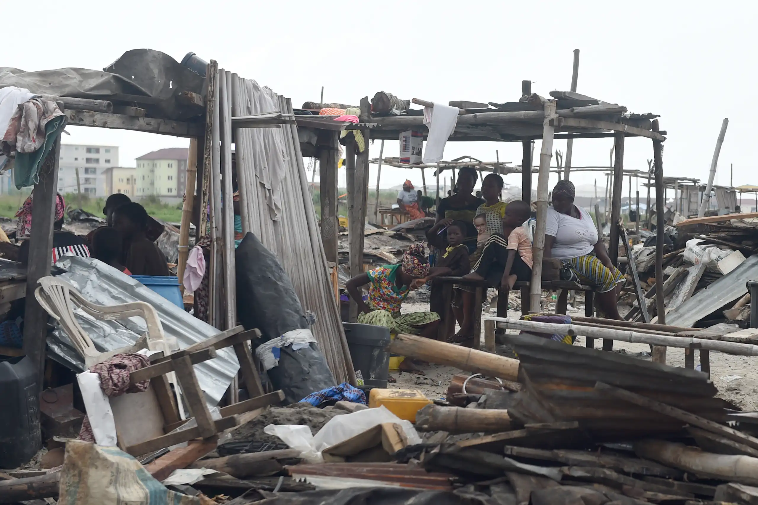 A group of people sitting in the wreckage of a demolished shelter