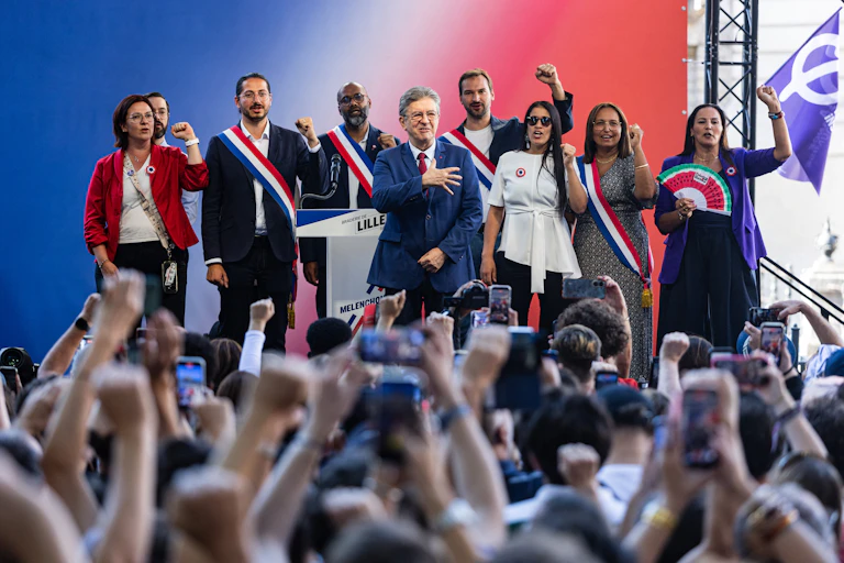 Sur l'estrade, les élus de LFI entourent J.-L. Mélenchon et chantent un hymne.