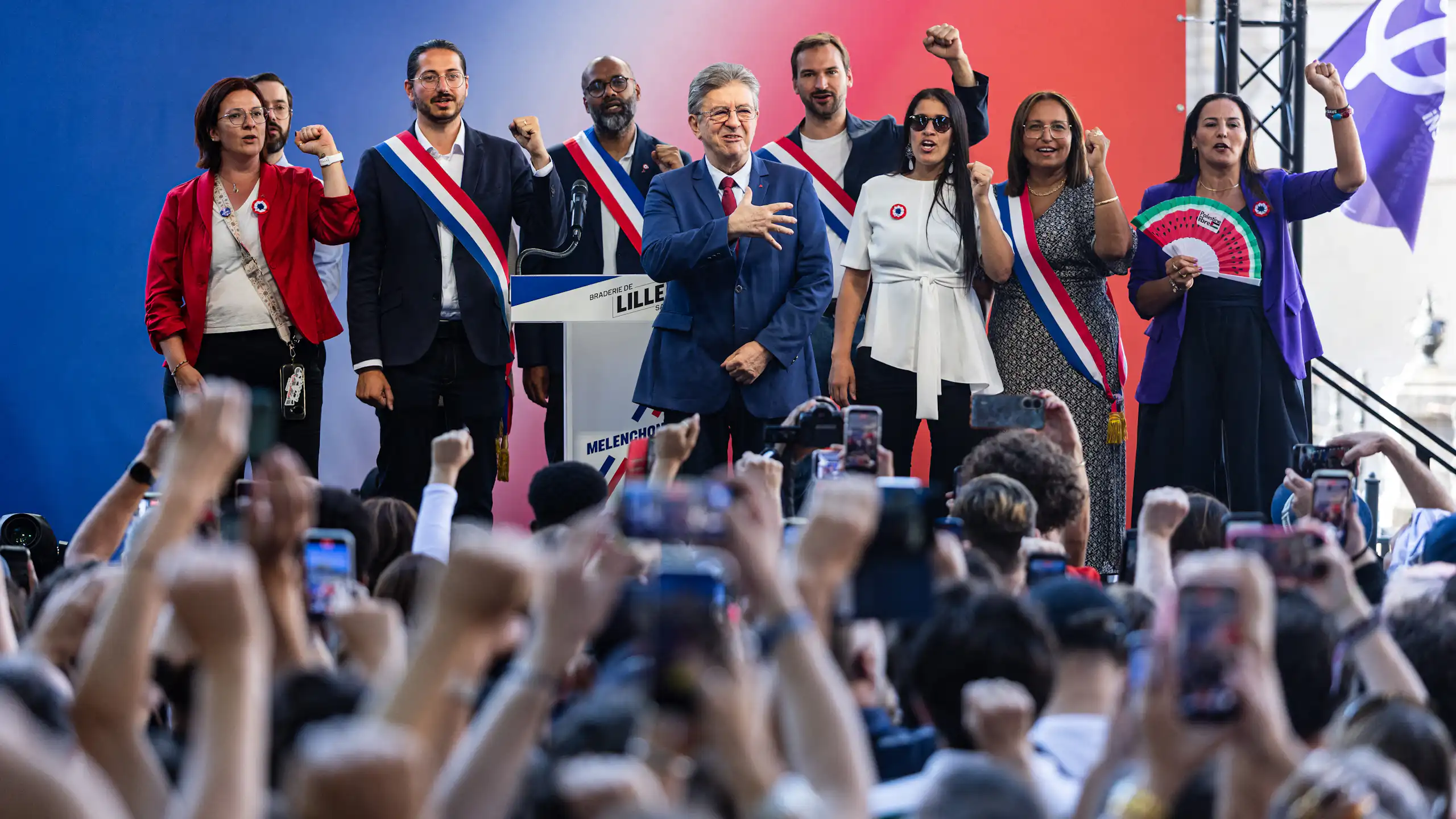 Sur l'estrade, les élus de LFI entourent J.-L. Mélenchon et chantent un hymne.