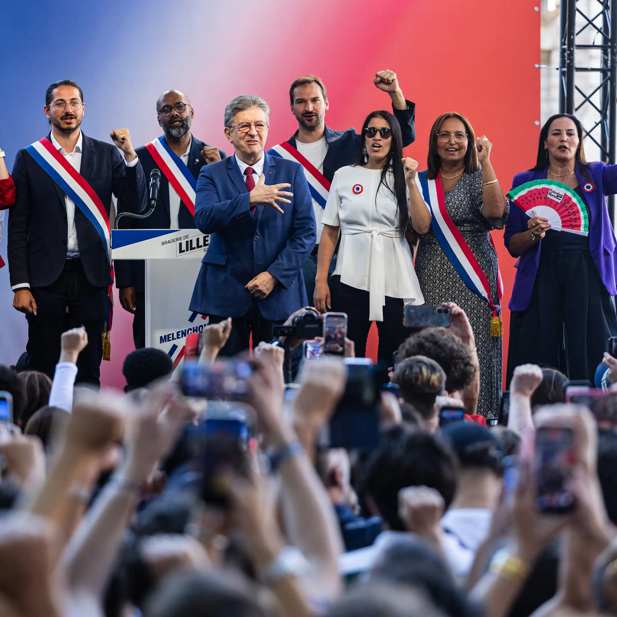 Sur l'estrade, les élus de LFI entourent J.-L. Mélenchon et chantent un hymne.