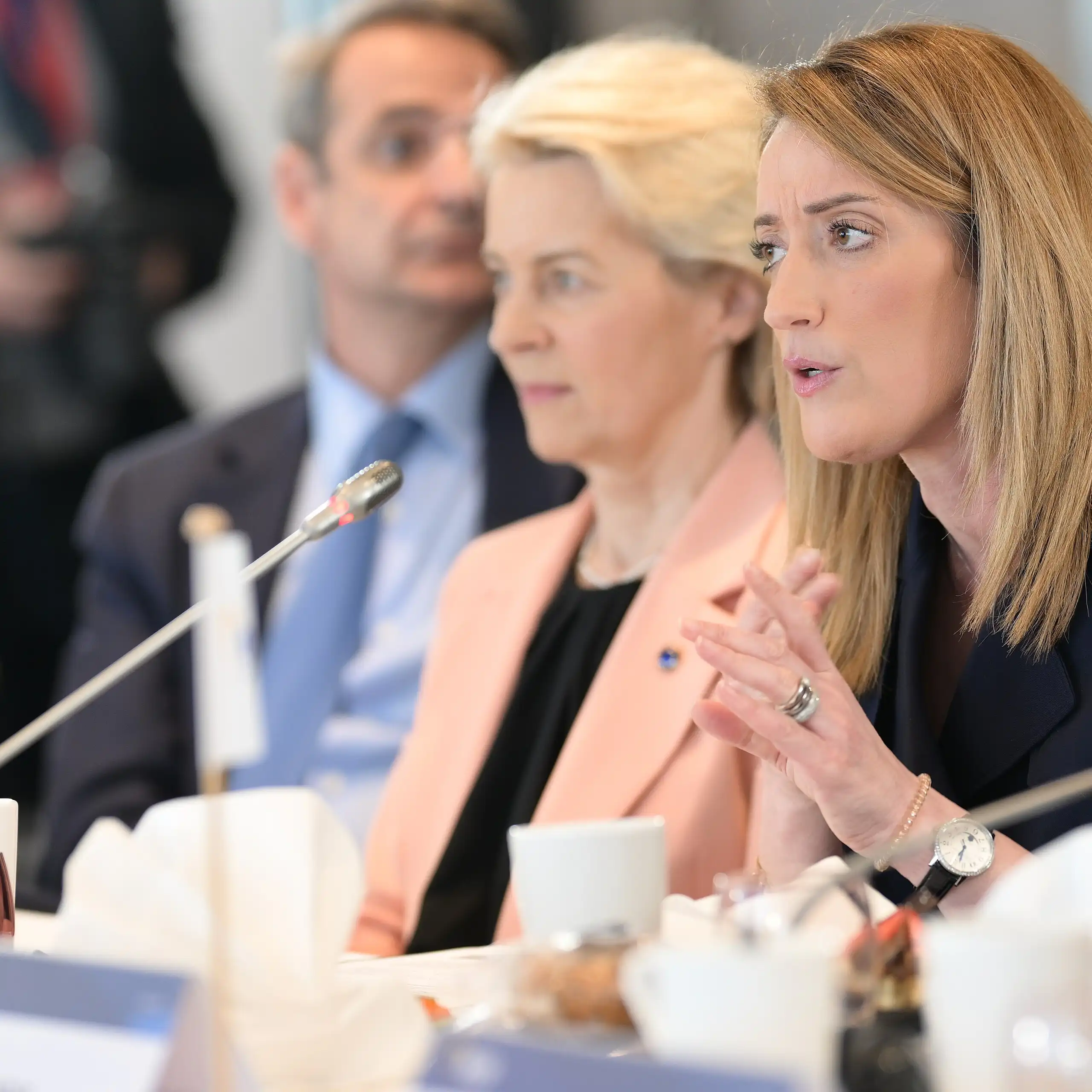 Roberta Metsola speaking into a microphone at a table, with Ursula von der Leyen sitting to her right