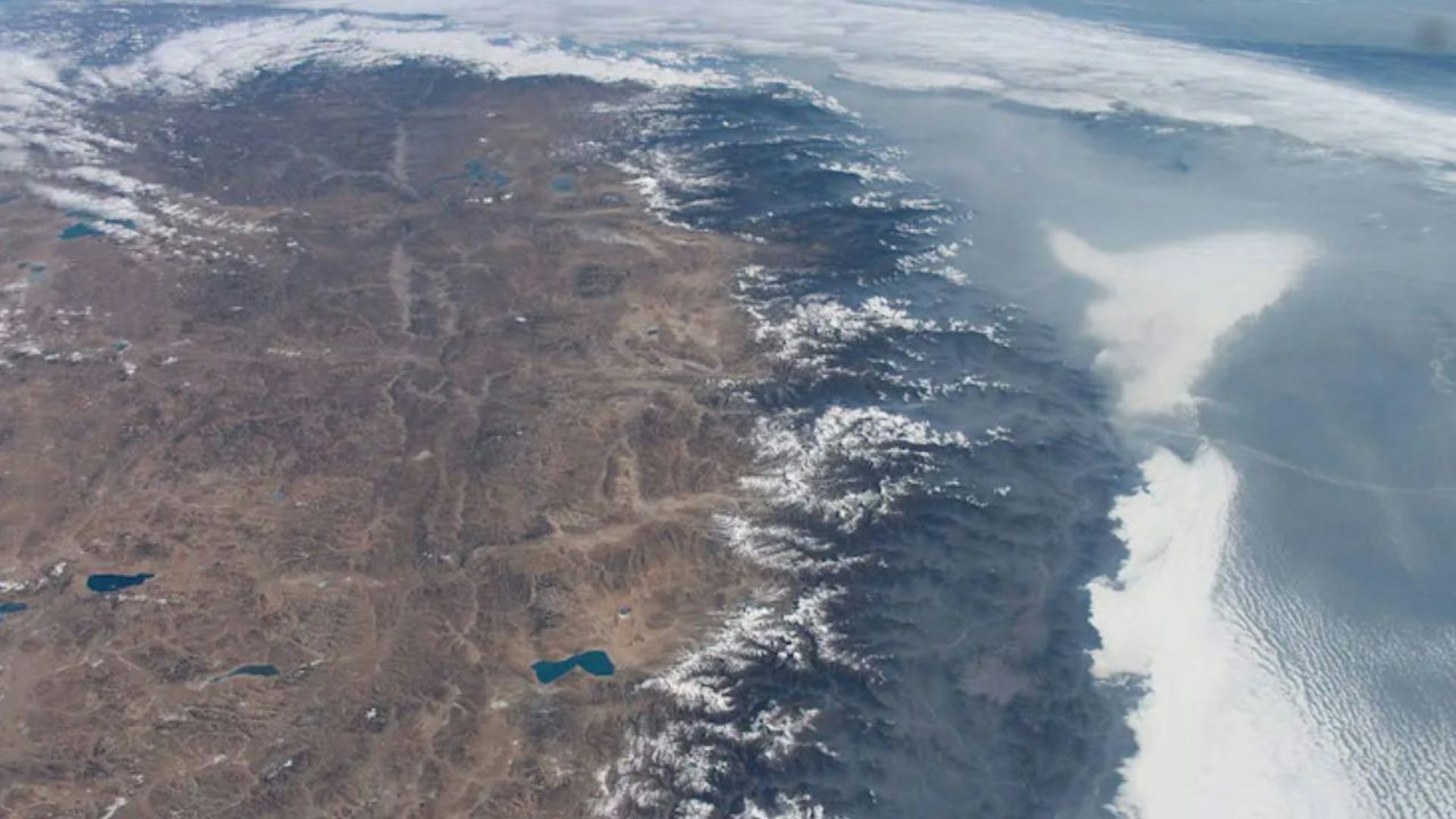 Brown Tibetan Plateau is on the left and the gray Himalyas mountains are in the middle. Photo is taken from space.