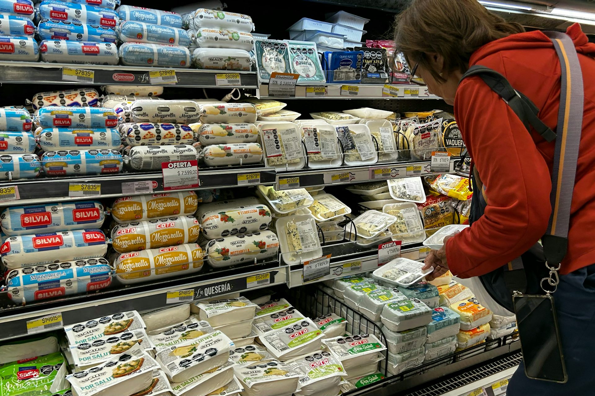 Une femme fait son choix dans un rayon de fromages.