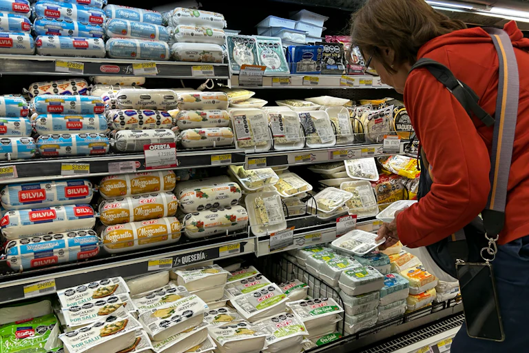 Une femme fait son choix dans un rayon de fromages.