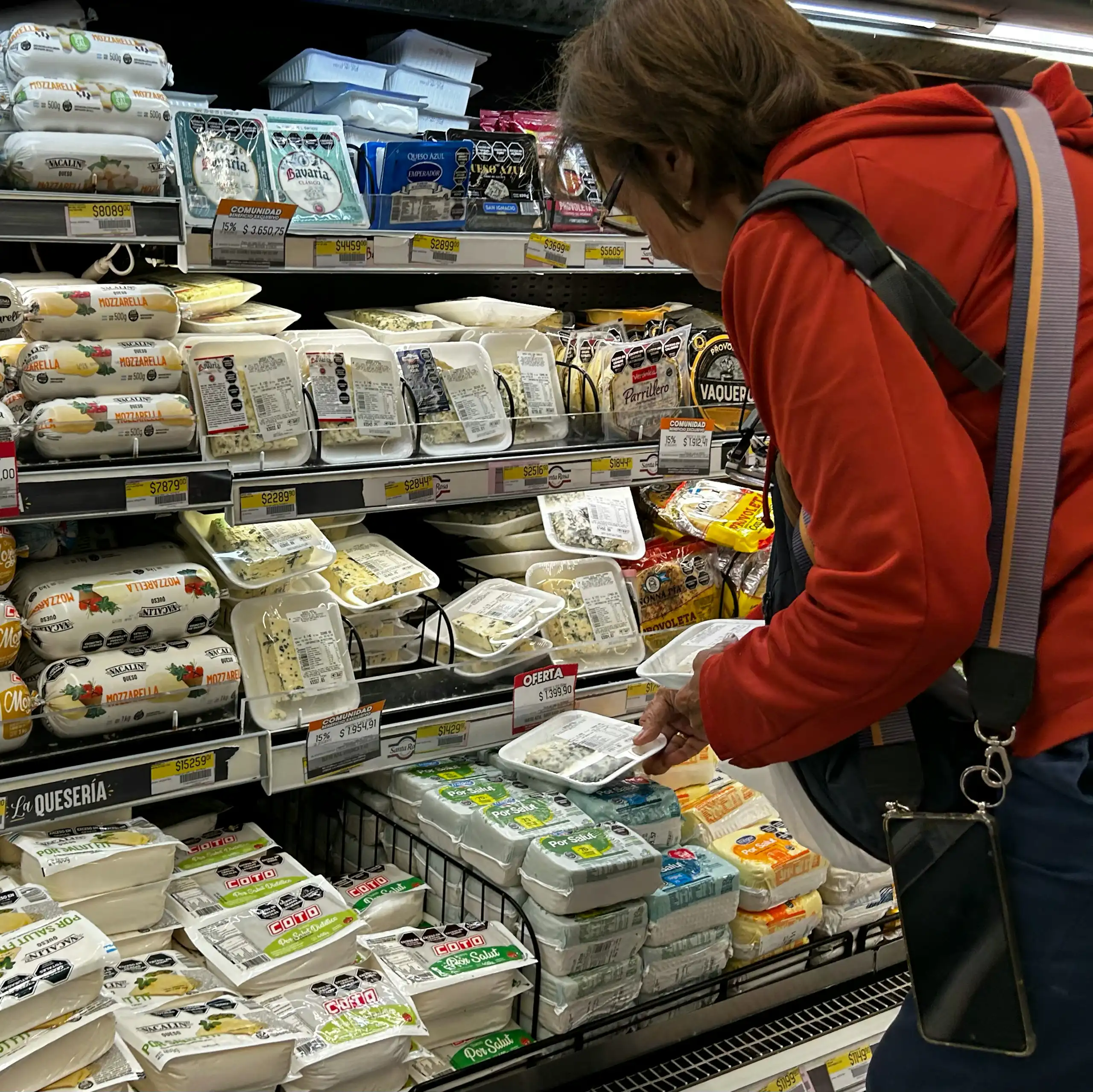 Une femme fait son choix dans un rayon de fromages.