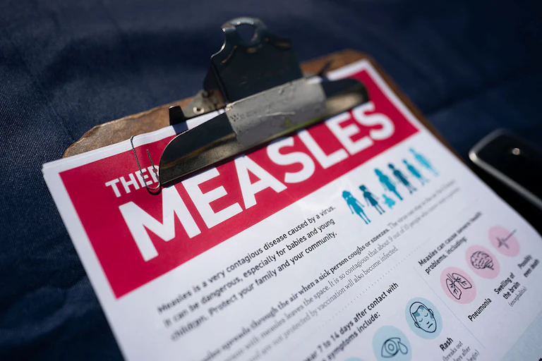 A clipboard holds an info sheet titled 'Measles.'