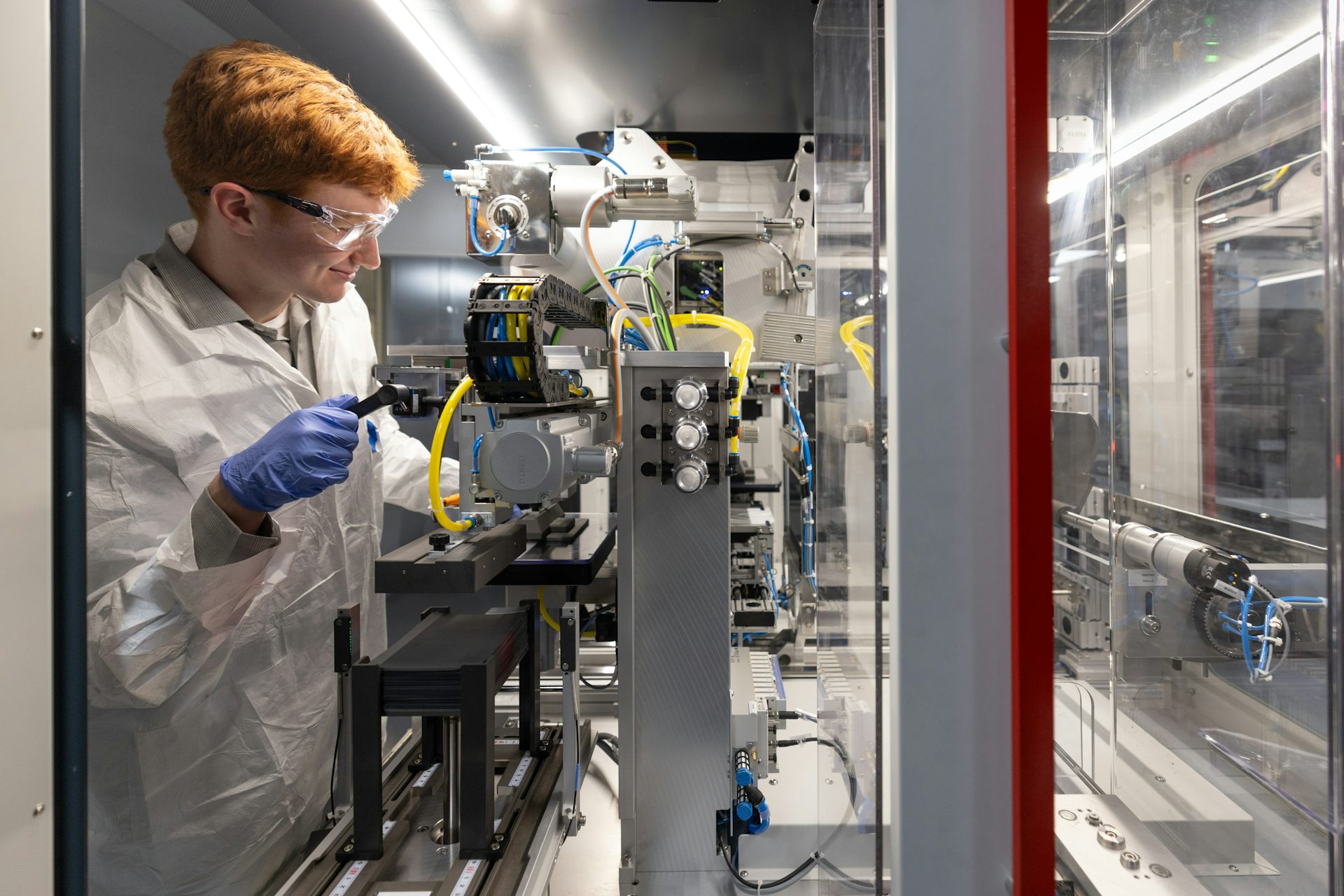 An intern in the clean energy program BATTERI calibrates an assembly stacker.
