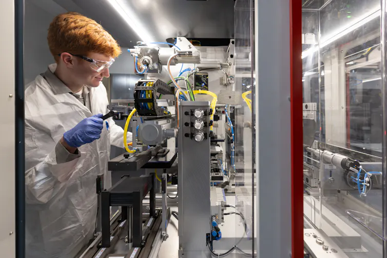 An intern in the clean energy program BATTERI calibrates an assembly stacker.