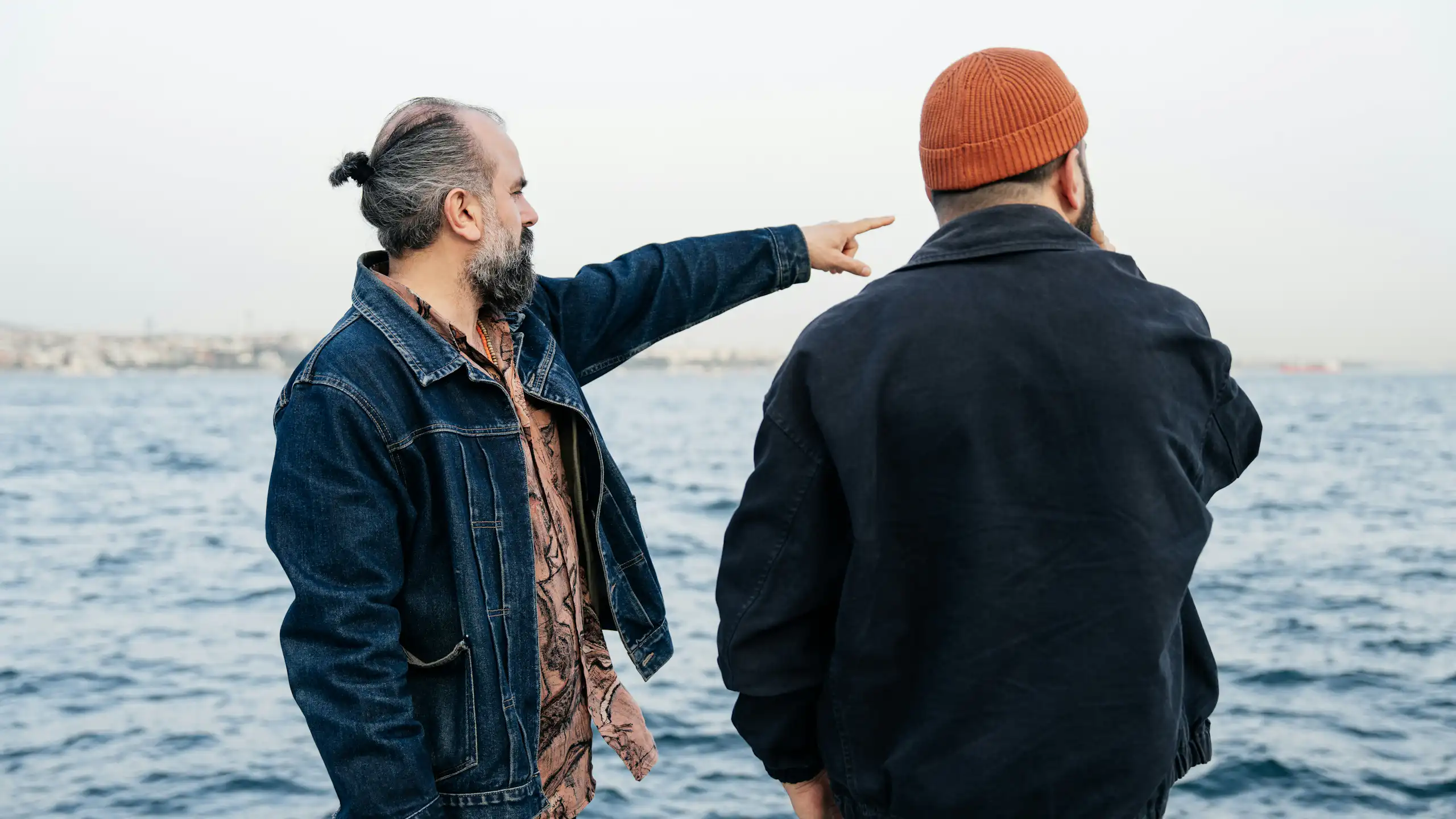 Two men look out at a body of water while they have a conversation.
