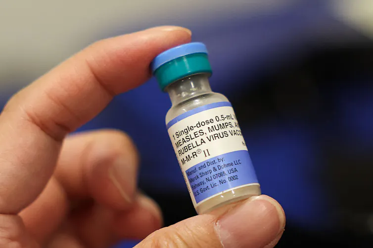 A small vial is held between a person's thumb and forefinger.