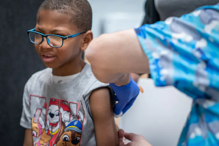 A young boy receives a shot in the arm.