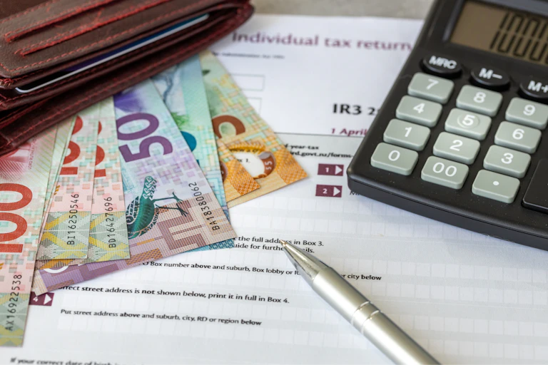 Collection of NZ currency, income tax form and calculator