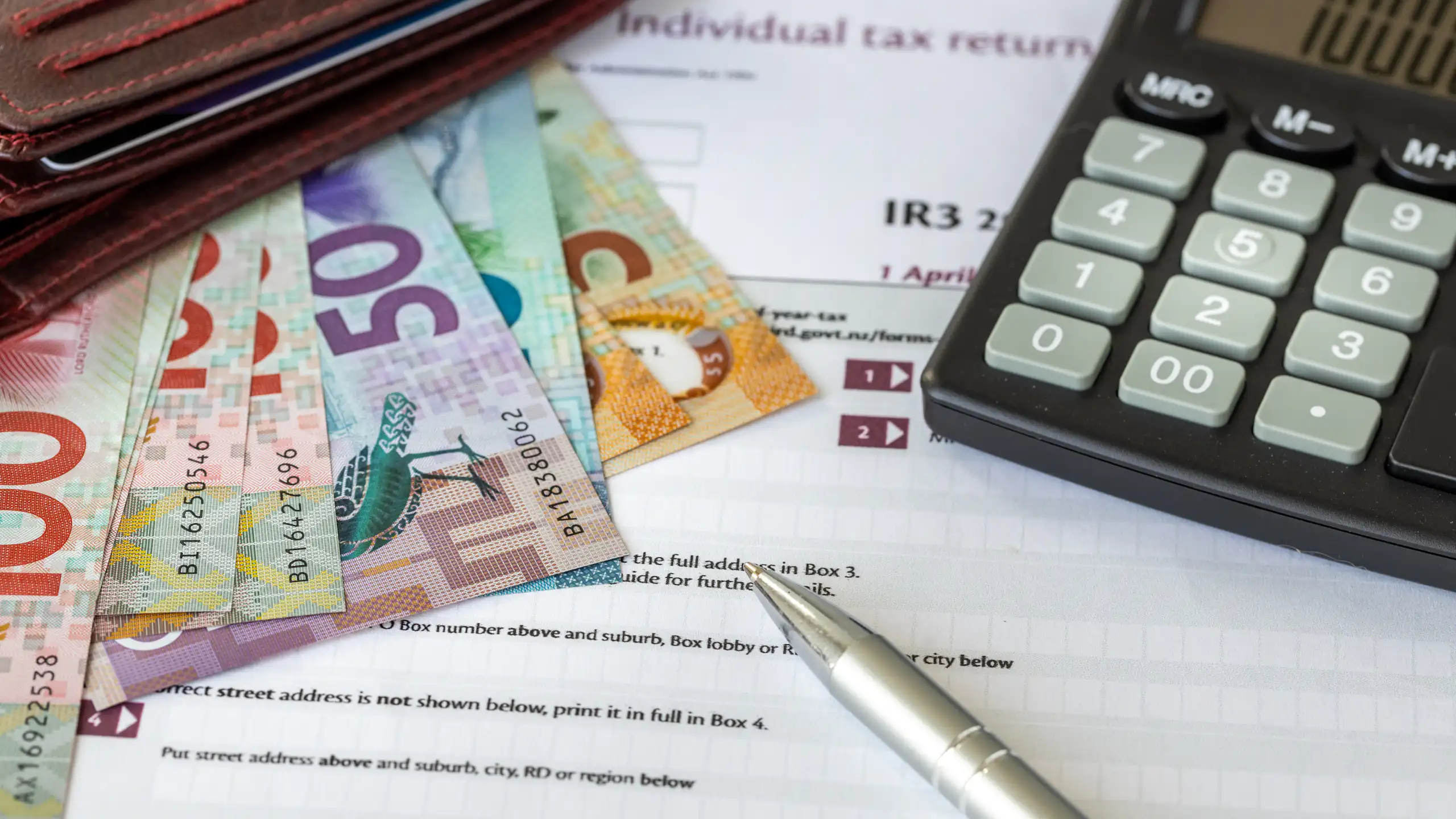 Collection of NZ currency, income tax form and calculator