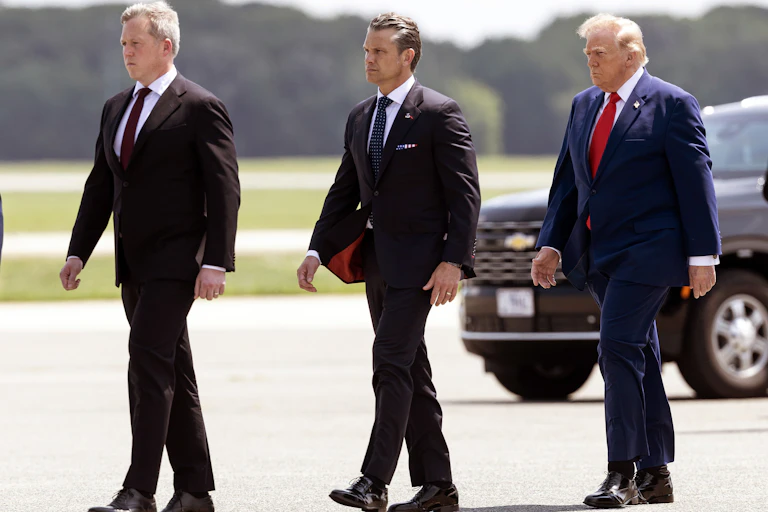 Dan Driscoll, Pete Hegseth and Donald Trump walk together across a tarmac.