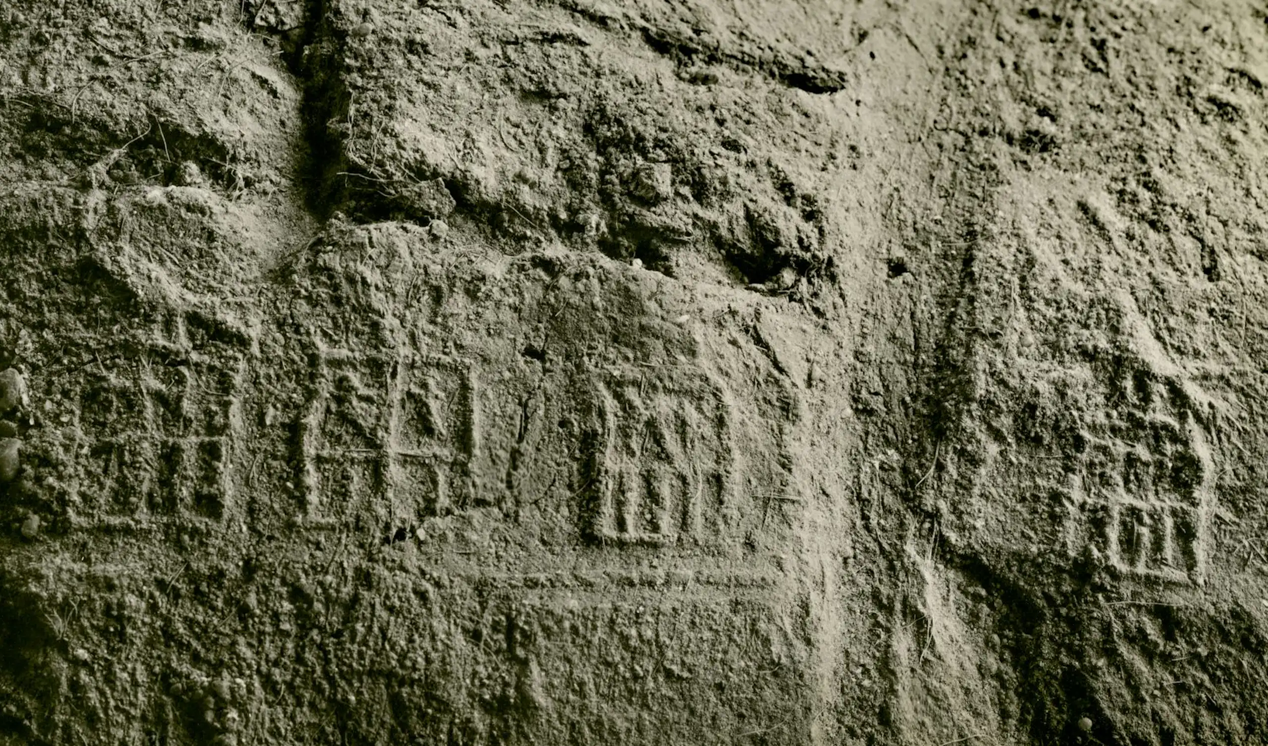 Close-up of inscriptions in a rough sand coloured surface.