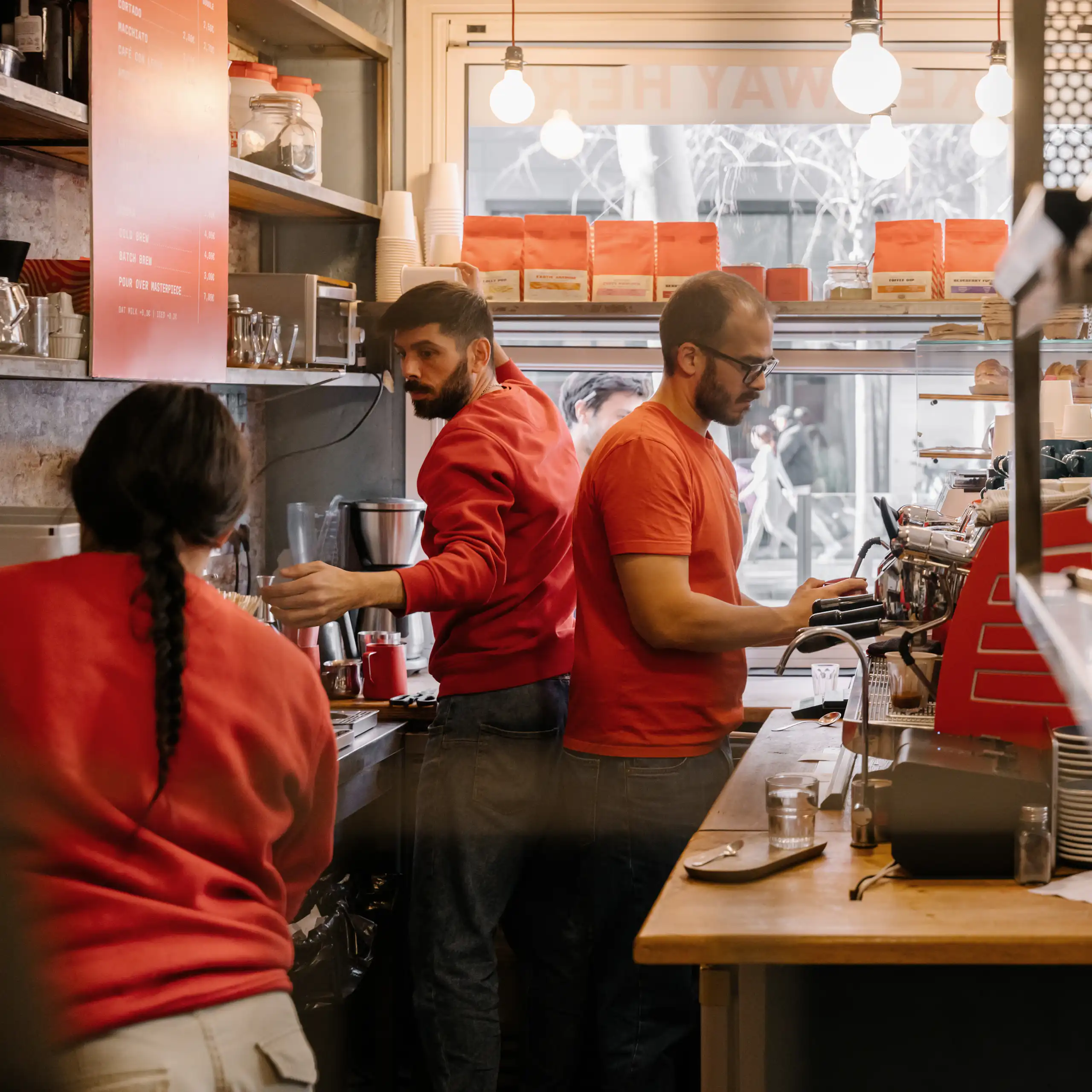 Three people work in a cafe kitchen