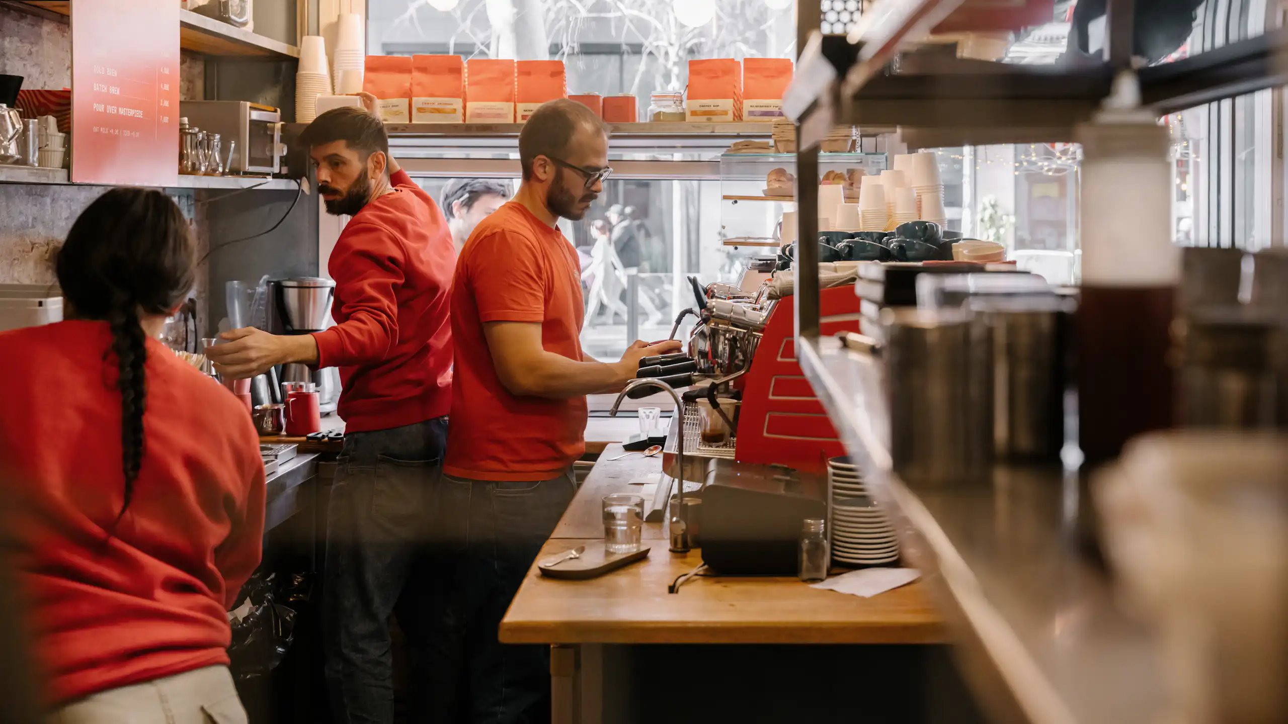 Three people work in a cafe kitchen