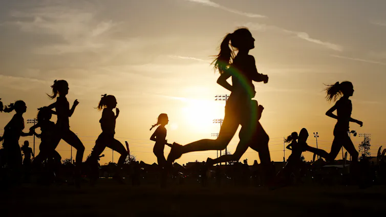 Women's silhouettes are seen during a fun run in a sunset.
