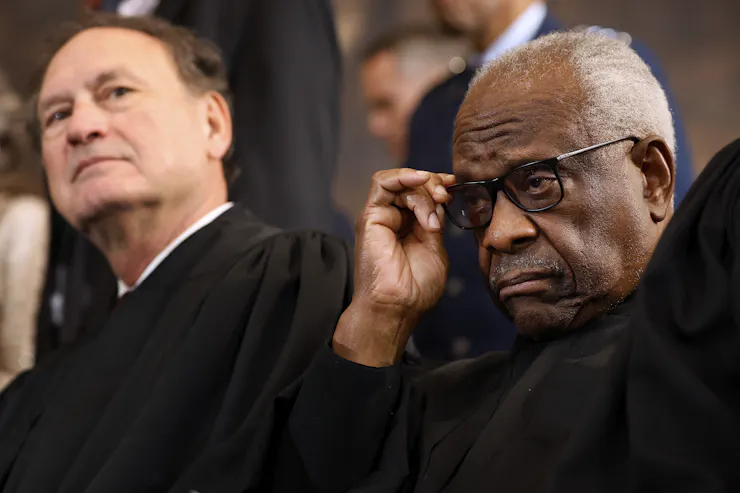 Two men in black robes, sitting next to each other.