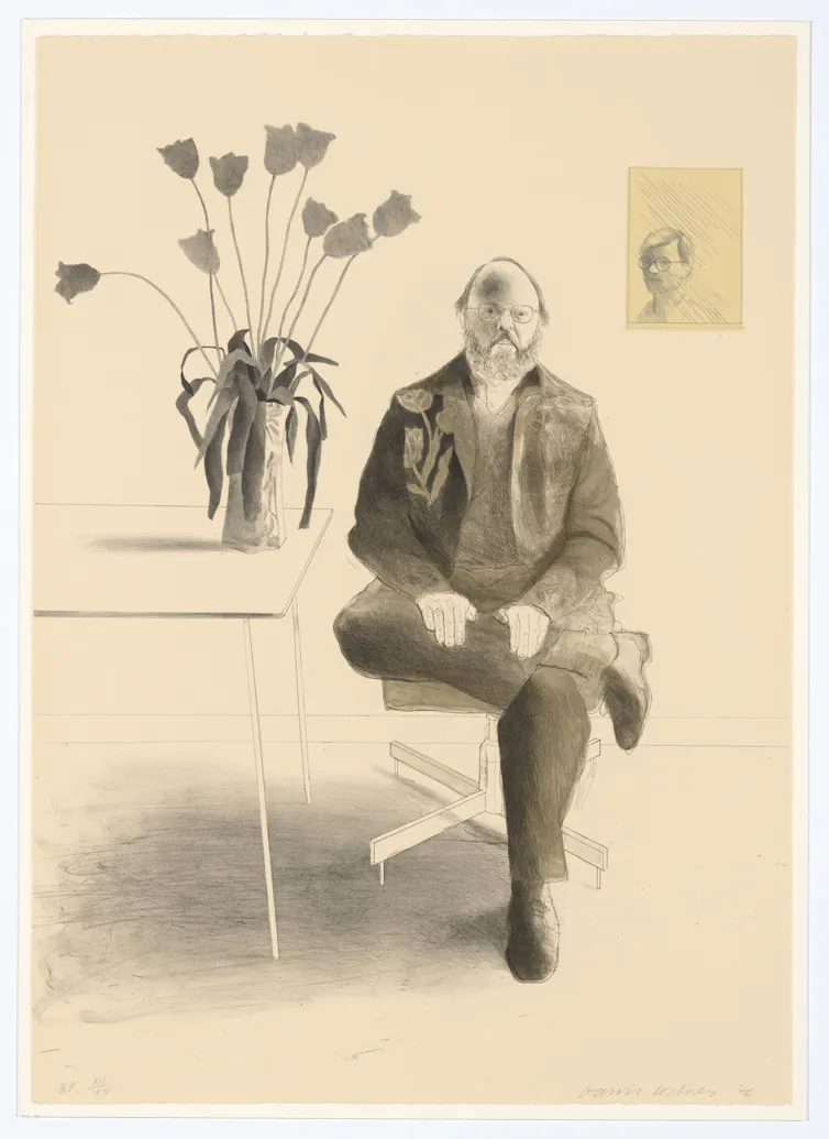 Framed portrait of a balding man sitting beside a table with a vase of tulips, in grey tones.