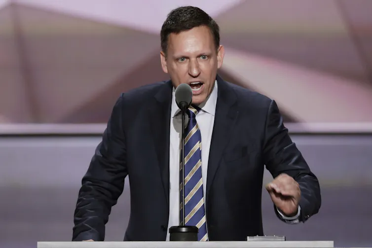 A man at a podium in suit and tie - Peter Thiel.