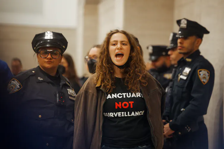 A woman being arrested by uniformed police, as she shouts.