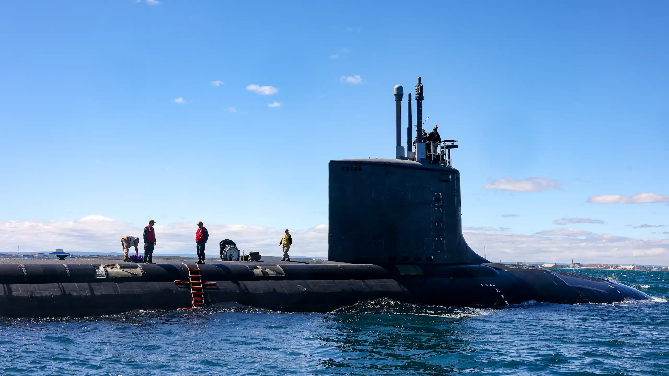 People stand aboard a submarine, submerged in the ocean